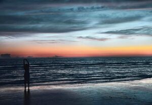 A person stretching at a beach in the evening